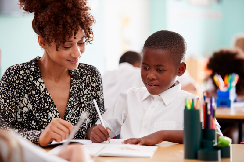 A teacher and student at The Genesis School in Cleveland, Ohio work together at a desk in a classroom.