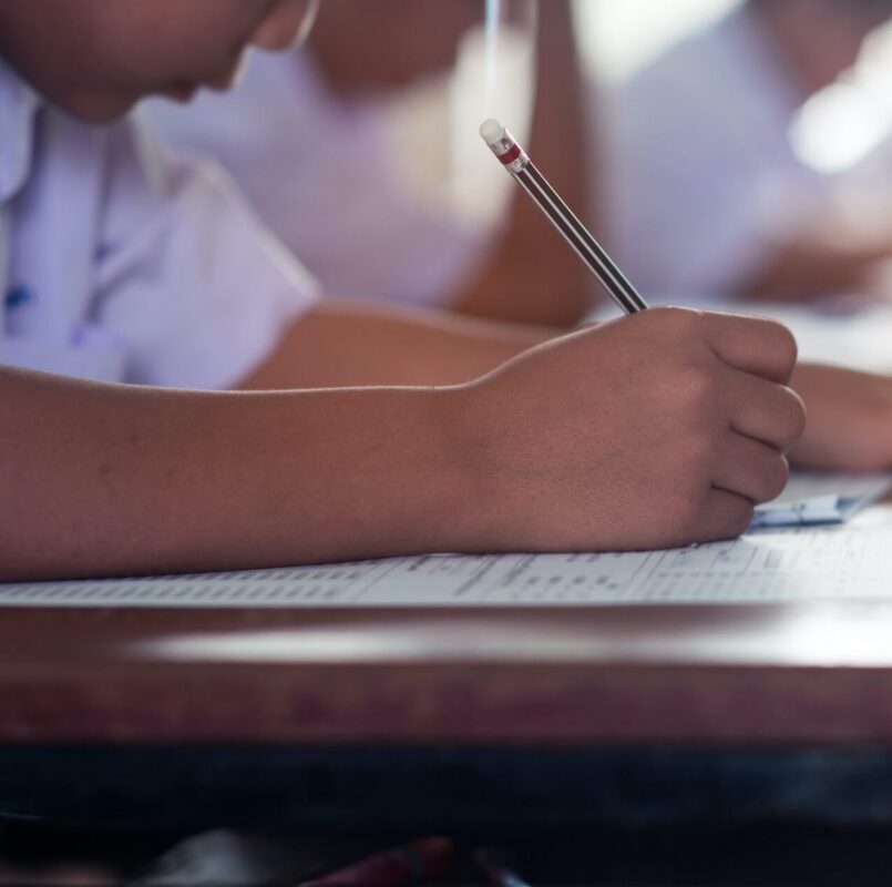 A student at a desk at The Genesis School holds a pencil.