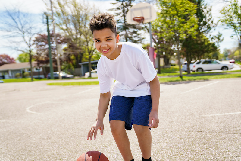 A scholar from The Genesis School in Cleveland dribbles a basketball on an outdoor basketball court